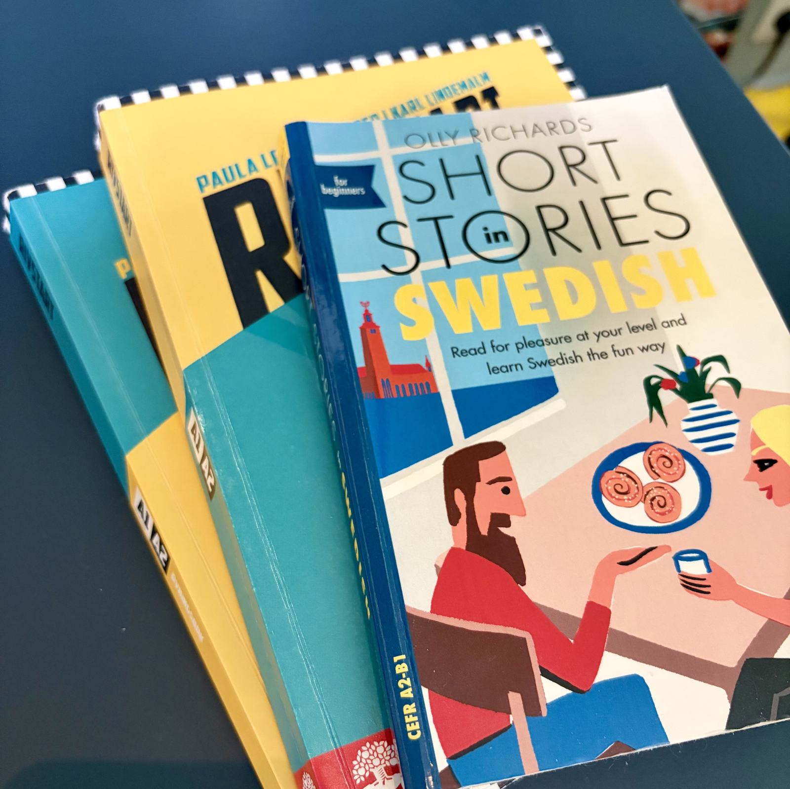 A pile of swedish class books (Rivstart A1 A2) and a smaller book titled "Short Stories Swedish"